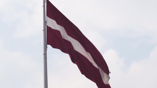 Letse vlag fladderen in de wind hoog in de lucht tijdens een gouden uur zonsondergang-Riga hoofdstad, Letland-Dambis AB enorme nationale vlag van het land — Stockvideo