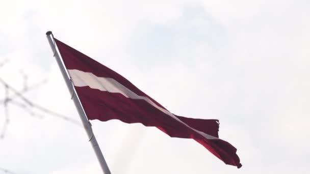 ゴールデンアワーの夕日の間に空高く風に揺れるラトビアの旗 - リガの首都、ラトビア - ダンビアブ巨大な国旗 — ストック動画