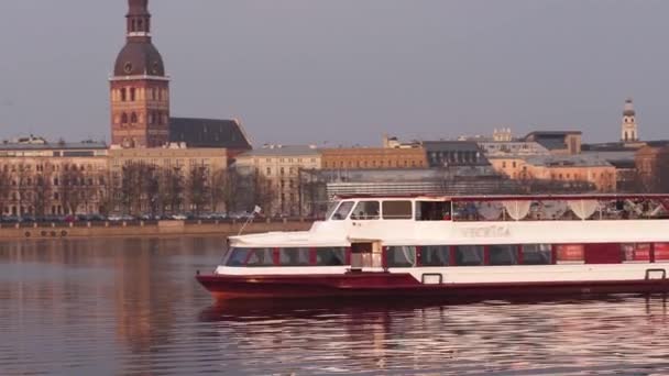 Riga, Lettland-april 7, 2019: båt Vecriga segling längs floden Daugava med utsikt över gamla stan i bakgrunden-östra Europas huvudstad under solnedgången gyllene timmen — Stockvideo