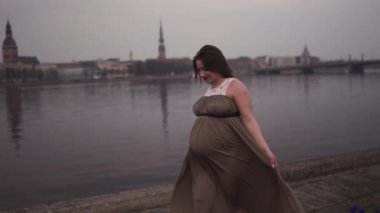 Genç hamile kadın seyahat yeri Letonya 'da Riga şehri ve Daugava nehrinin manzarasıyla mutlu.