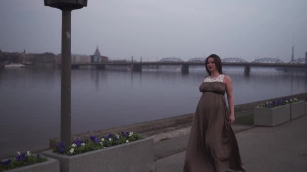 Young pregnant woman is happy in her travel destination country Latvia with a view over city Riga and river Daugava - White caucasian girl wearing maternity dress — Stock Video