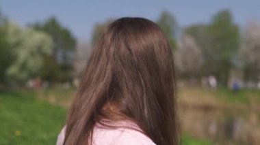 Yavaş Hareket 120fps: Genç mutlu gezgin kahverengi saçlı kadın kız gülümseyen ve Baltık eyaletlerinde pembe bir sakura kiraz çiçeği ağaçları ile yeni bir hedef ülkede etrafında dönüyor - Uçan saç