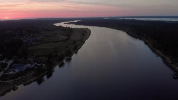 空中トップビューは、真紅の紫とピンクの空と日の出の間にユルマラ、ラトビアの春2019のリレルペ川の上を飛ぶ - 太陽はかろうじて示しています — ストック動画