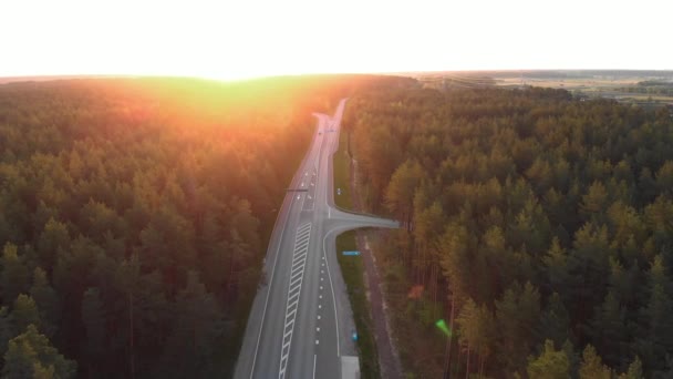 Aerial sunrise shot of road outside city in a countryside forest with cards and trucks passing buy - Follow vehicle shot - Vista superior desde arriba — Vídeos de Stock