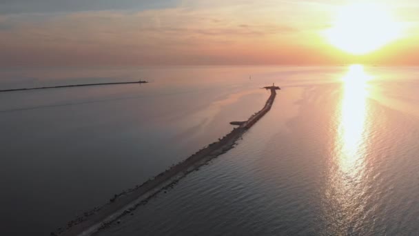 Início do pôr-do-sol aéreo Vista do farol com navios em segundo plano Cenário de paisagem solar quente durante a Hora Dourada Rio Daugava juntando-se ao golfo do Mar Báltico em Mangalsala, Letônia — Vídeo de Stock