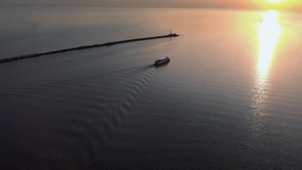 Follow white ship yacht - Aerial sunset top Lighthouse view with ships in the background - Warm setting sun landscape scenery during Golden Hour — Stock Video