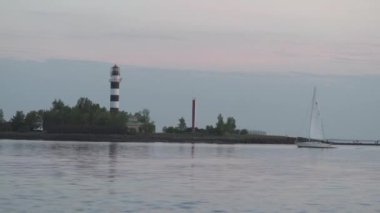 Gün batımı veya gün doğumu sırasında bir Deniz Feneri tarafından Nehir Daugava boyunca yüzme küçük yat - Kremsi manzara sahne - Zephyr cupcake renkleri