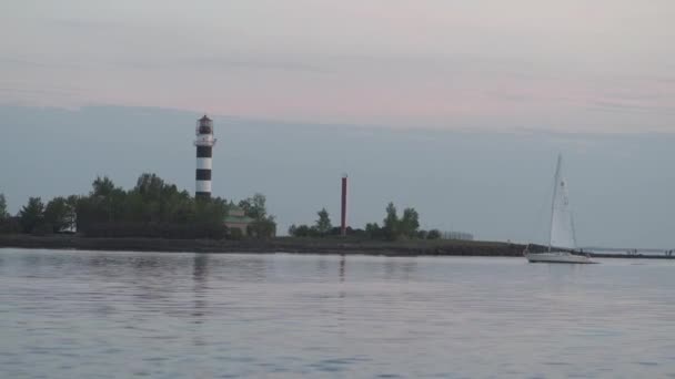 Kleine jacht zwemmen langs de rivier de Daugava door een vuurtoren tijdens zonsondergang of Sunrise-romige landschap landschap-Zephyr cupcake kleuren — Stockvideo