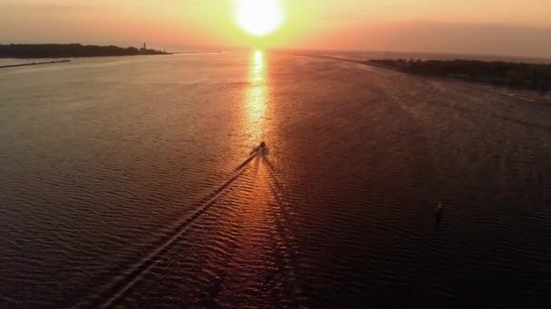 追跡ボート船に続く - 非常に少ない雲と暖かい夕暮れで空中灯台壮大な映画撮影 - 上の川からのドローンビューはバルト海湾に入る - 滑らかなプロのndフィルターの動き — ストック動画