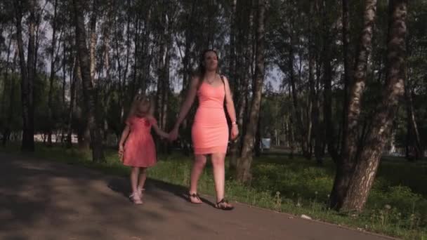 Щаслива мати грає зі своєю маленькою дочкою-дівчинкою і отримує задоволення - молода біла мама в літньому яскравому кольоровому одязі - концепція сім'ї щастя — стокове відео