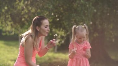 Üfleme karahindiba - Mutlu anne onun küçük bebek kız kızı ile oynarken ve eğlenmek - Genç kafkas beyaz anne yaz parlak canlı renk elbise giyiyor - Happinness aile konsepti