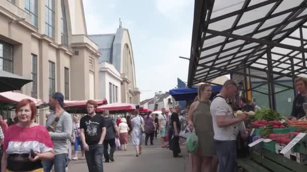 Riga, Lotyšsko-květen 21, 2019: centrální trh centralais tirgus plný turistů a místních hledaje nákup jídla a zeleniny-venkovní pohled na staré německé Zepelinové hangáry — Stock video