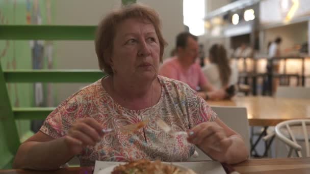 Mayor pelirroja senior retiredf viajar turista mujer come en restaurante cafetería con luz rosa camiseta con poco profundo dop profundidad de campo — Vídeos de Stock