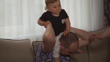 Aile değerleri: Anne ve baba bebek çocuk çocuk kapalı ile oynarken - Ebeveynler mavi ve gri ev giyim ve oğulları siyah beyaz giyen - Mutlu gülümseyen insanlar