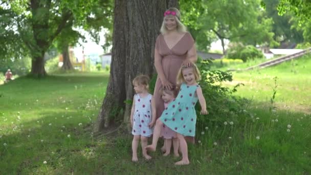 Mladá blondýnka hippie matka mít kvalitní čas se svými holčičkami v parku - Dcery nosit podobné šaty s jahodovým potiskem - Rodinné hodnoty - 1, 2, 6 let staré děti na slunném jarním dni — Stock video