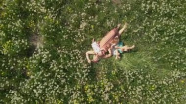 Anten: Genç sarışın hippi anne kaliteli zaman bir park karahindiba alanında onun bebek kız ile yatarken sahip - Kızları çilek baskı ile benzer elbiseler giymek - Aile değerleri