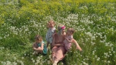 Anten: Genç sarışın hippi anne bir park karahindiba alanında onun bebek kız ile oturan kaliteli zaman sahip - Kızları çilek baskı ile benzer elbiseler giymek - Aile değerleri