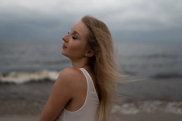 Close up retrato de bela jovem loira praia ninfa em vestido branco perto do mar com ondas durante um tempo sombrio maçante com vento tempestuoso e chuva — Fotografia de Stock