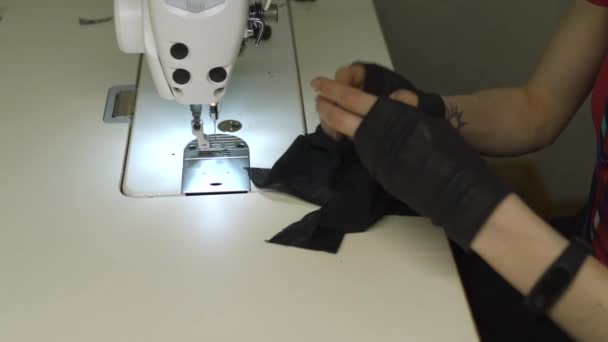 Diseñadora de moda cyber punk en el trabajo en su estudio de costura con máquina - Mujer blanca caucásica con camiseta roja y guantes negros con tijeras colgando sobre su pecho — Vídeo de stock