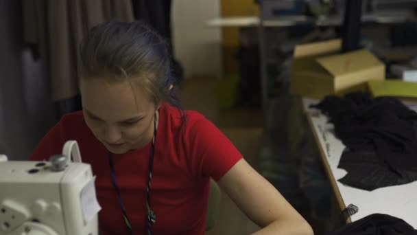 Cyber-Punk-Modedesignerin bei der Arbeit in ihrem Atelier Nähen mit der Maschine - kaukasische weiße Frau trägt rotes T-Shirt und schwarze Handschuhe mit Schere über der Brust — Stockvideo