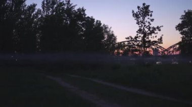 Riga, Letonya şehir parkında canlı günbatımı renkleri pembe ve arka planda mor ve korkunç duman yüzen ürkütücü akşam sis