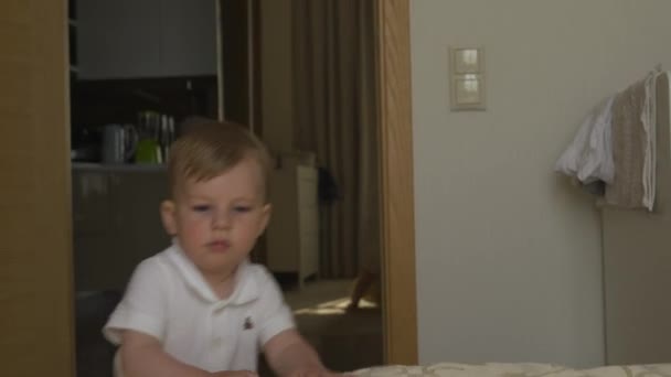男婴肖像在公寓周围走来走去是好奇和快乐的笑容穿着白色身体马球 - 家庭价值观的目标 - 白种人母亲和孩子在家里 — 图库视频影像