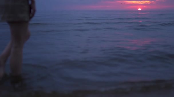 Frau nackte Beine aus nächster Nähe zu Fuß Wasser - erstaunlich dunkel szenisch lebhaft purpurroten seltenen roten Sonnenuntergang mit violetten und magentafarbenen Farben an der Ostsee mit kleiner Sonne am Horizont — Stockvideo