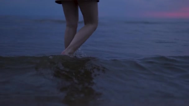 Frau nackte Beine aus nächster Nähe zu Fuß Wasser - erstaunlich dunkel szenisch lebhaft purpurroten seltenen roten Sonnenuntergang mit violetten und magentafarbenen Farben an der Ostsee mit kleiner Sonne am Horizont — Stockvideo