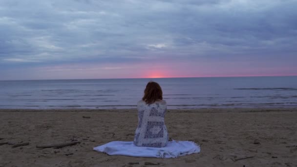 Jonge vrouw meisje in een witte jurk zitten op de voorgrond op een deken en genieten van zeldzame gloeiende natuur hemel - Verbazingwekkende donkere schilderachtige levendig karmozijn zeldzame rode zonsondergang — Stockvideo