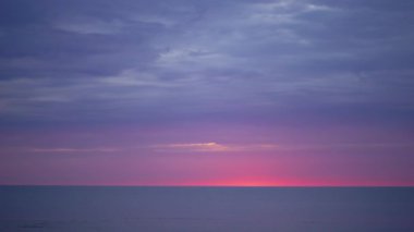 Ufukta küçük güneş ile Baltık Denizi'nde mor ve macenta renkleri ile Inanılmaz karanlık doğal canlı kırmızı kırmızı gün batımı