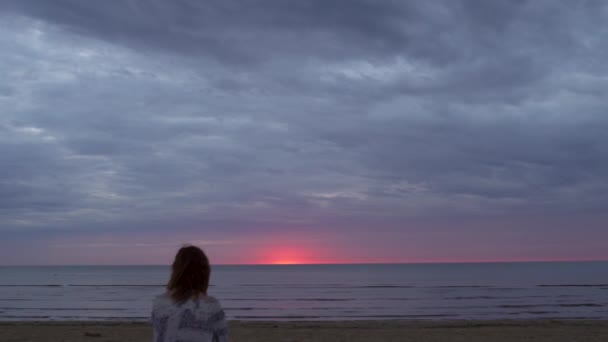 Young woman girl in a white dress sitting in the foreground on a blanket and enjoying rare glowing nature sky - Amazing dark scenic vivid crimson rare red sunset — 비디오