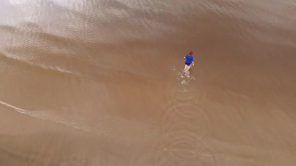 Aéreo: Jovem mulher de vestido azul brilhante andando por aí - Paisagem de pôr do sol amarelada cênica de águas rasas no Mar Báltico - Vista de voo de drones de cima — Vídeo de Stock