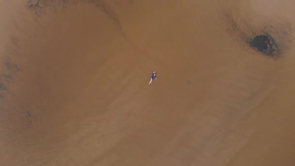 Aéreo: Jovem mulher de vestido azul brilhante que estabelece - Paisagem de pôr do sol amarelada cênica de água rasa no Mar Báltico - Vista de voo de zangão de cima — Vídeo de Stock