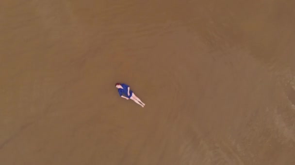 Hava: Mavi parlak elbiseli genç kadın - Baltık Denizi'nde sığ su manzaralı sarımsı günbatımı manzara - Yukarıdan drone uçan görünümü — Stok video