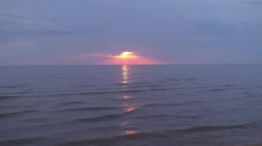 Ufukta küçük güneş ile Baltık Denizi'nde mor ve macenta renkleri ile Inanılmaz karanlık doğal canlı kırmızı kırmızı gün batımı