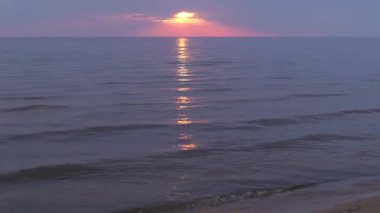 Ufukta küçük güneş ile Baltık Denizi'nde mor ve macenta renkleri ile Inanılmaz karanlık doğal canlı kırmızı kırmızı gün batımı