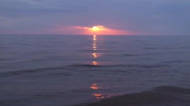 Ufukta küçük güneş ile Baltık Denizi'nde mor ve macenta renkleri ile Inanılmaz karanlık doğal canlı kırmızı kırmızı gün batımı