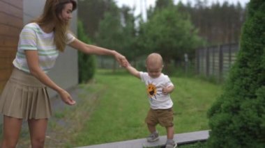 Genç anne oyun ve oyuncaklar ile bir bahçede onun bebek erkek erkek kardeşi ile eğlenmek - Aile değerleri sıcak renk yaz sahnesi