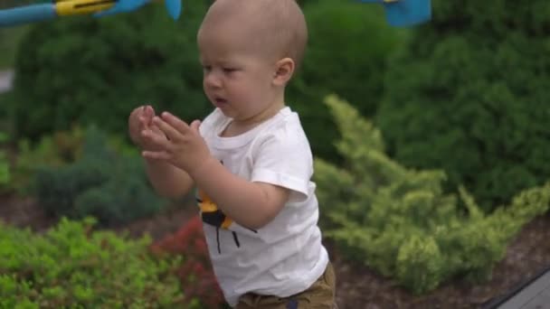 Jonge baby jongen zoon kreeg gesneden in een tuin met speelgoed - Familie waarden warme kleur zomer scene — Stockvideo