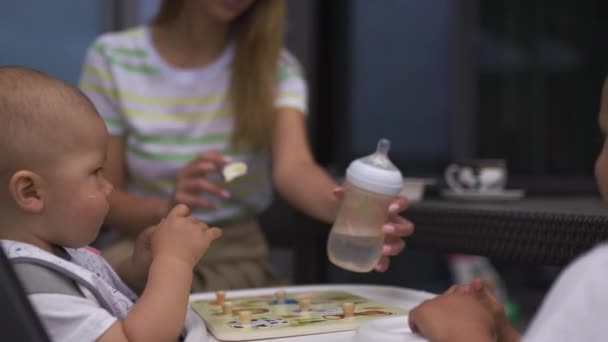 Junge Mutter füttert ihren kleinen Sohn im Kindersitz - Familie schätzt warme Farbe im Sommer — Stockvideo