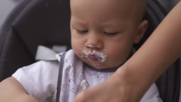 Обличчя крупним планом смішні білі вуса: молода мама годує свого сина хлопчика сидячи на дитячому сидінні - Сім'я цінує теплий колір літньої сцени — стокове відео