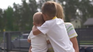 Genç anne yeşil bir bahçede küçük oğluyla oynuyor ve eğleniyor. Aile değerleri sıcak yaz manzarası. Letonya bayrağı.