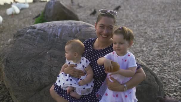 Young mother with her baby girl daughters smiling and looking at camera at a river wearing dotted dress - Family values warm color summer scene — 비디오