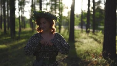Ayakta: Geleneksel Letonya Ligo yaz ortasında bir Çelenk redhead genç kadın - Beyaz beyaz kız güneşli gün batımında bir kemer ile noktalı bir yaz elbise giyiyor