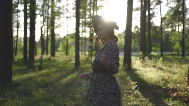 Walking: Redhead ung kvinna i en krans under traditionell lettiska Ligo midsommar dag-kaukasiska vit flicka klädd i en prickig sommarklänning med ett bälte i solig solnedgång — Stockvideo