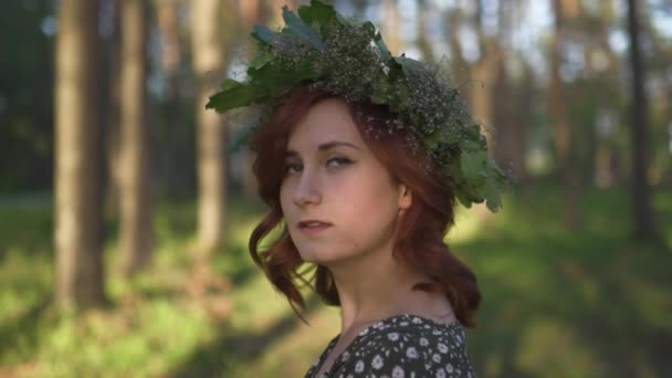 Face närbild: Redhead ung kvinna i en krans under traditionell lettisk Ligo midsommar dag-kaukasiska vit flicka klädd i en prickig sommarklänning med ett bälte i solig solnedgång — Stockvideo