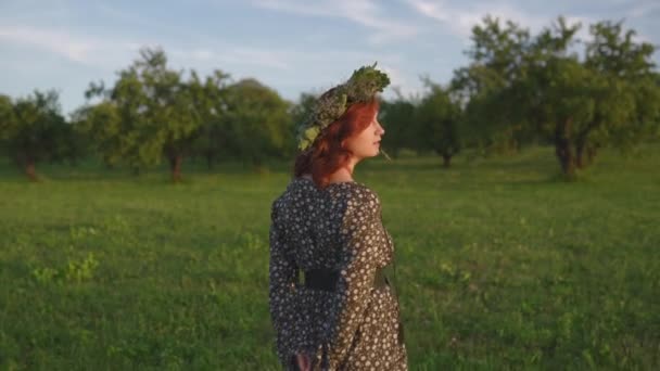 Rothaarige junge Frau im Kranz während des traditionellen lettischen ligo Mittsommertages - kaukasisches weißes Mädchen in einem gepunkteten Sommerkleid mit Gürtel im sonnigen Sonnenuntergang — Stockvideo