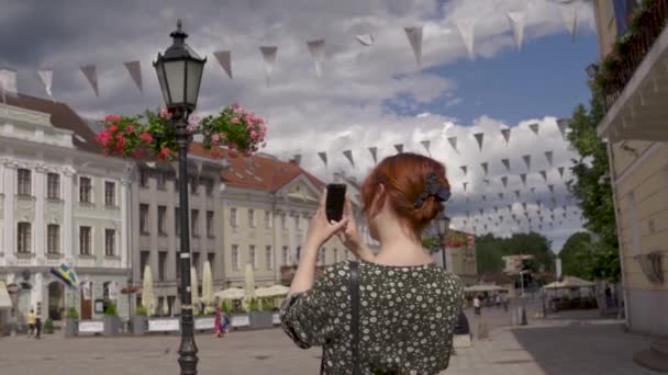 Femme rousse touristique dans une belle ville européenne Tartu, Estonie fille blanche caucasienne portant une robe d'été pointillée — Video