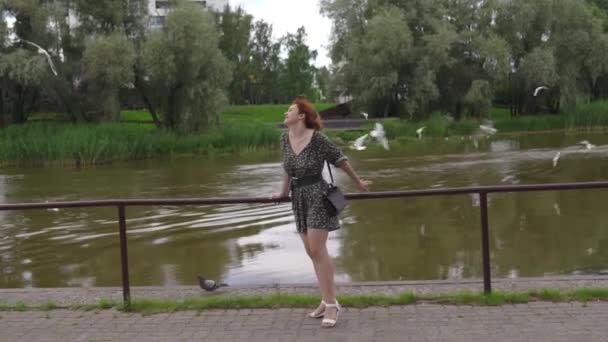 Touriste rousse femme profiter de la journée avec des oiseaux volant en arrière-plan - fille blanche caucasienne portant une robe d'été en pointillés — Video
