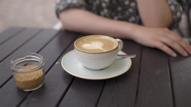 Turista pelirroja sentada en una cafetería bebiendo café capuchino - Caucásico chica blanca con un vestido de verano punteado — Vídeo de stock